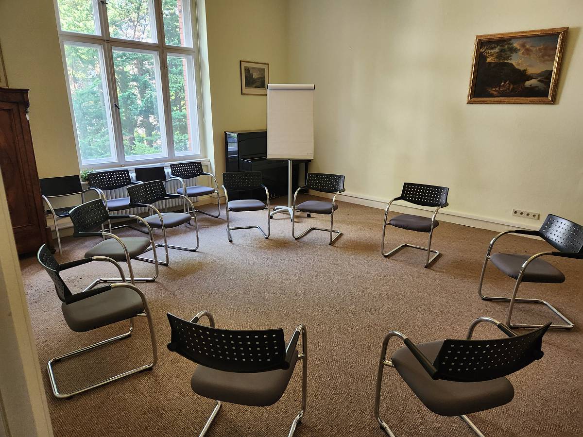 Seminarraum mit Stuhlkreis, Flipchart und großem Fenster für Selbsterfahrung und Gruppengespräche.